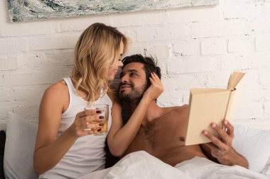 happy tender couple with rea reading book together in bed in the morning  clipart