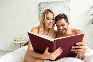 Neşeli çift sabahları yatakta kitap okuyor. 