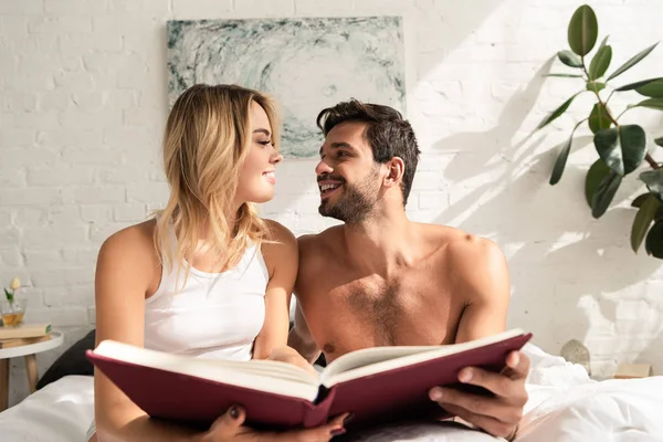 Happy Couple Holding Book Looking Each Other Bed Morning — Zdjęcie stockowe