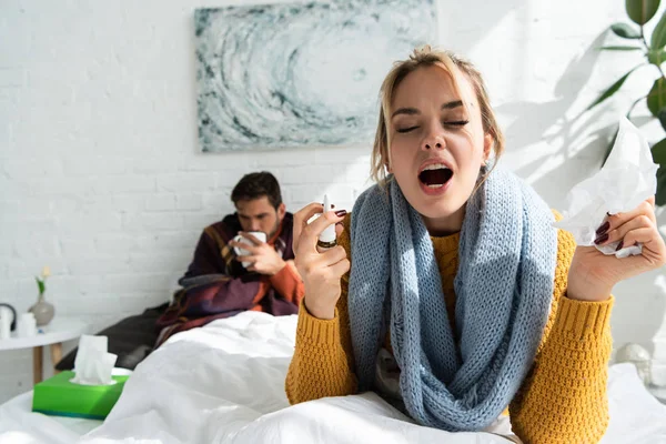 Mujer Enferma Estornudando Sosteniendo Aerosol Nasal Servilletas Dormitorio Con Hombre — Foto de Stock