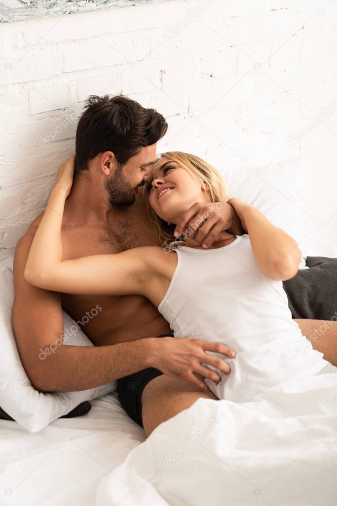 beautiful smiling couple embracing in bed in the morning 