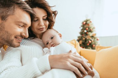 Mutlu adam, annesinin ellerinde uzanan sevimli küçük kızına bakıyor.