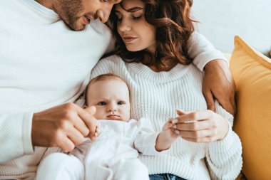 Kırpılmış bir adamın güzel karısını kucaklaması, küçük kızını kucağına alması.