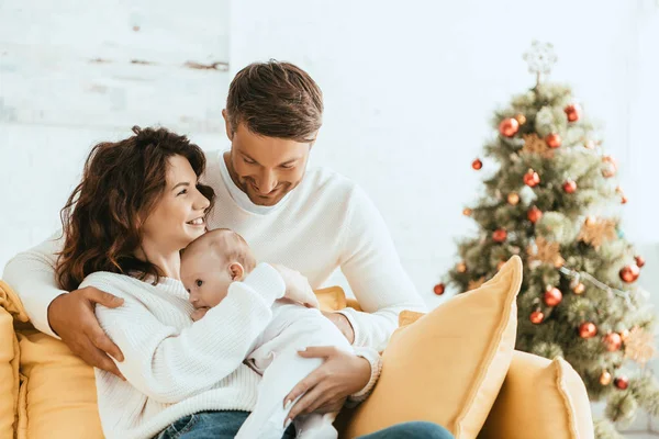 Happy Man Hugging Wife Sitting Yellow Sofa Baby Christmas Tree — Stock Photo, Image