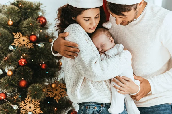幸福的父亲在圣诞树旁拥抱可爱的妻子 抱着可爱的孩子 — 图库照片