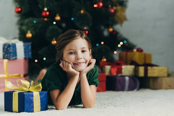 快乐的孩子躺在礼品盒旁的地板上 对着相机微笑 — 图库照片