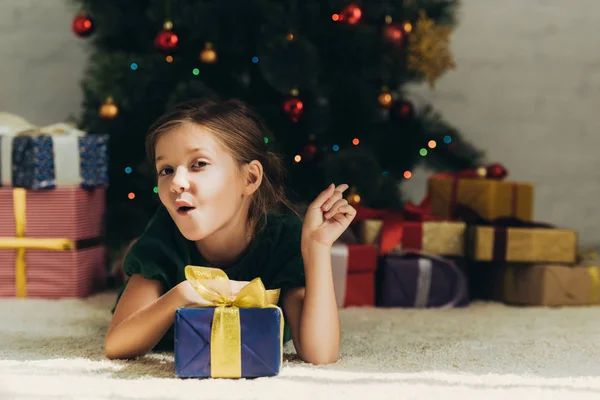 Amused Child Pointing Finger Gift Boxes While Lying Floor Christmas — Stock Photo, Image