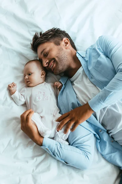 Vista Dall Alto Felice Padre Abbracciando Adorabile Bambino Mentre Sdraiato — Foto Stock