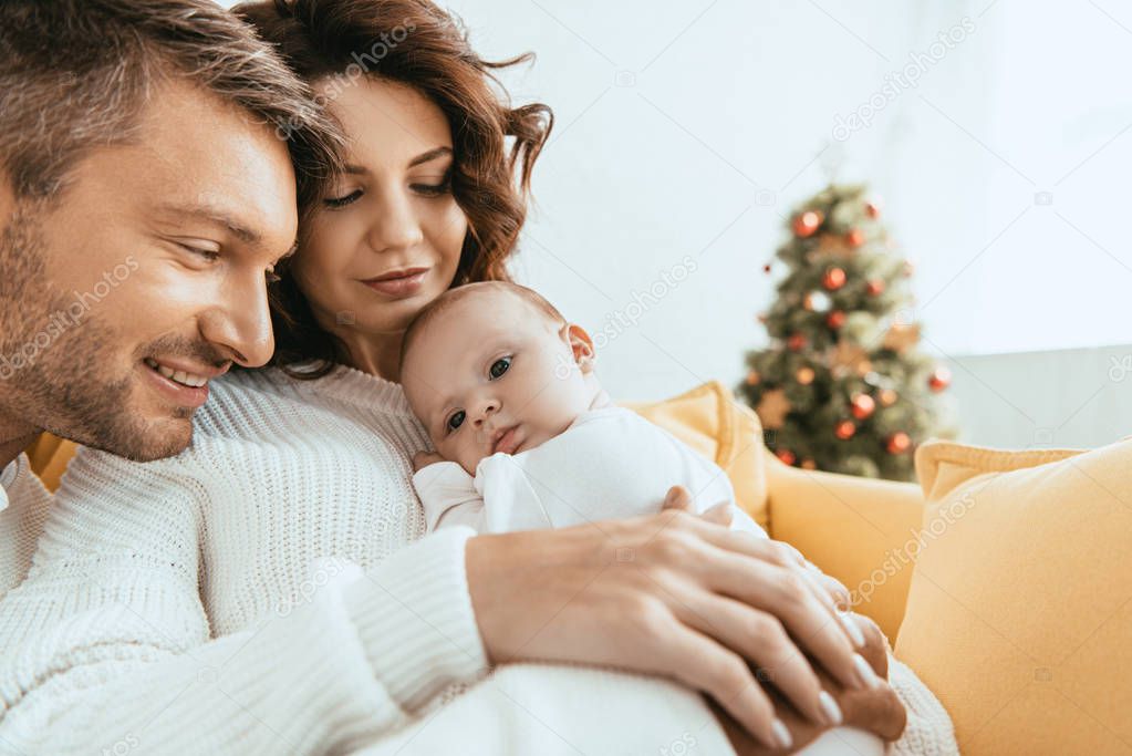 happy man looking at adorable little daughter lying on mothers hands