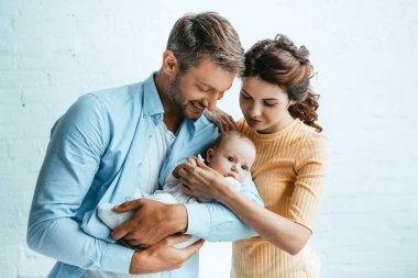 Çekici kadın mutlu kocanın yanında duruyor kucağında küçük bir çocuk var.