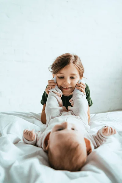 Enfoque Selectivo Niño Feliz Tocar Las Piernas Bebé Adorable Acostado —  Fotos de Stock