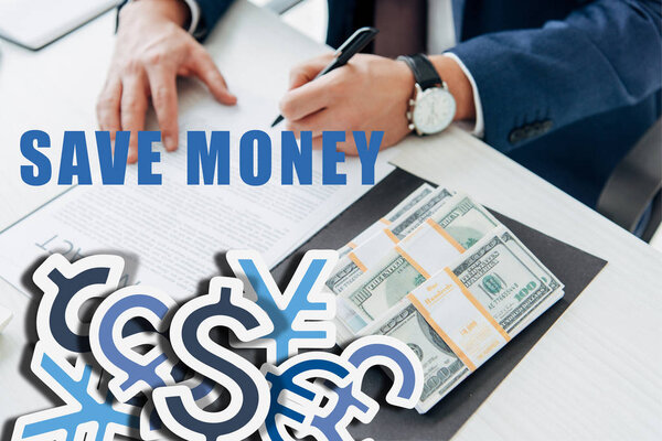 cropped view of businessman signing contract near money in office with save money illustration