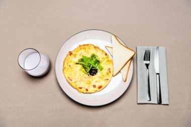 Omlet manzarası, çatal, bıçak ve bir bardak yoğurt tabakta. 