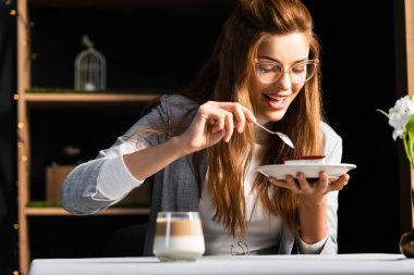 Kahveli kek yiyen neşeli, çekici bir kadın. 