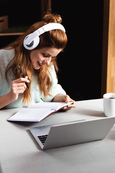 在网吧里带着笔记本电脑在网上写作和学习的快乐女人 — 图库照片