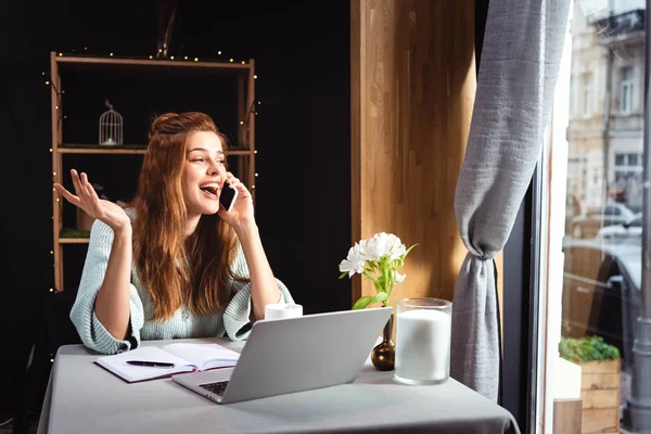 Mujer Emocionada Hablando Teléfono Inteligente Mientras Trabaja Ordenador Portátil Cafetería — Foto de Stock