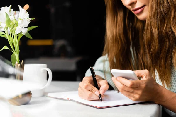 Cropped View Woman Using Smartphone Writing Notepad Cafe Cup Coffee — Stock Photo, Image