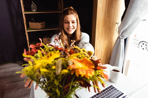 Kahvesinde Bir Buket Sonbahar Çiçeğiyle Gülümseyen Kızıl Saçlı Kadın Dizüstü — Stok fotoğraf