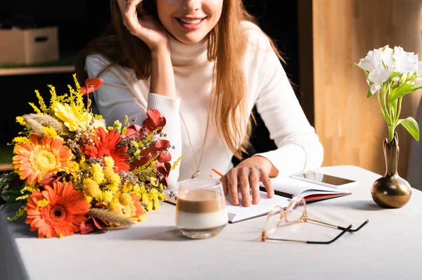 Kafede Elinde Bir Buket Sonbahar Çiçeği Olan Akıllı Telefon Defterli — Stok fotoğraf