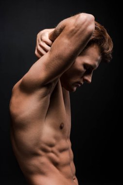 Yakışıklı seksi adam, siyah üzerinde yalnız poz veriyor.