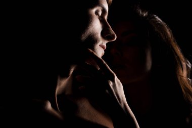 Güzel, seksi çift sarılıyor, arka planda siyah ışıkta izole edilmiş.
