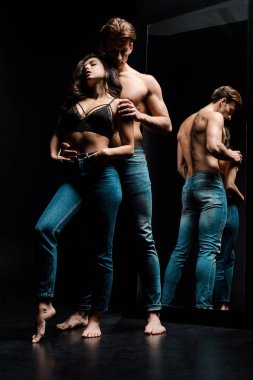 Yakışıklı adam aynanın yanında seksi kadına sarılıyor.