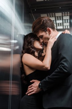 Güzel, baştan çıkarıcı bir çift asansörde sarılıp öpüşüyor.