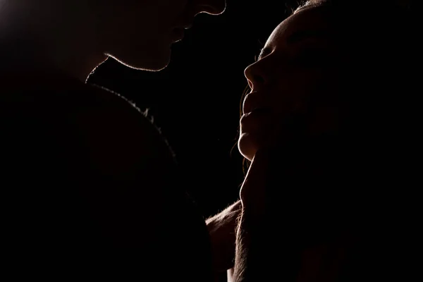 美しい親密なカップルの抱擁 バックライトと黒に隔離された — ストック写真
