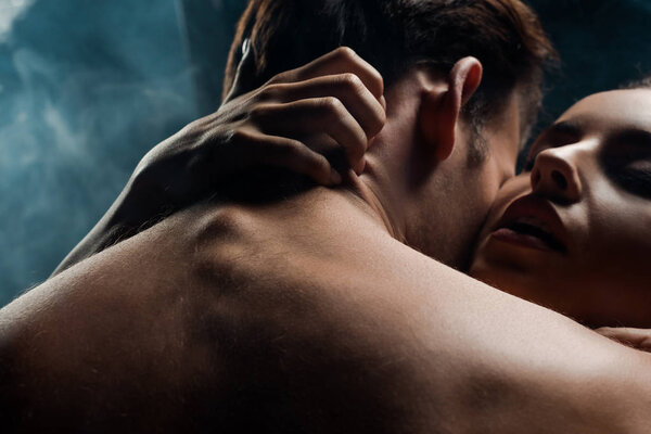 passionate couple hugging in black room with smoke