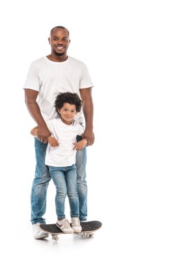 Mutlu Afro-Amerikan erkeği beyaz arka planda duran sevimli oğlunu destekliyor.