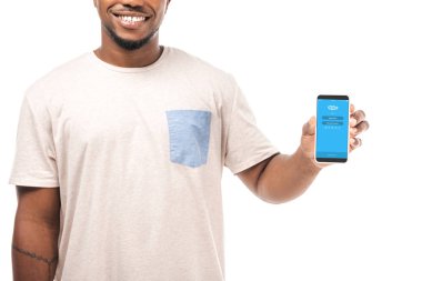 Kyiv, Ukrayna - 15 Ağustos 2019: Beyaz ekranda Skype uygulaması ile akıllı telefon tutan gülümseyen Afrikalı Amerikalı adamın kısmi görüntüsü.
