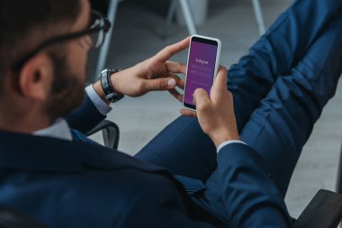 Kyiv, Ukrayna - 1 Ekim 2019: Instagram uygulaması ile akıllı telefon tutan işadamlarının seçici odak noktası.
