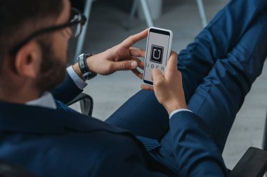 Kyiv, Ukrayna - 1 Ekim 2019: Uber uygulaması ile akıllı telefon kullanan işadamlarının seçici odak noktası.