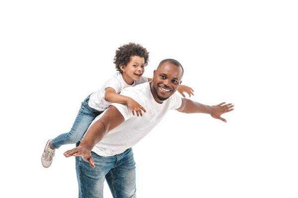 happy african american man piggybacking adorable son and imitating flying on white background