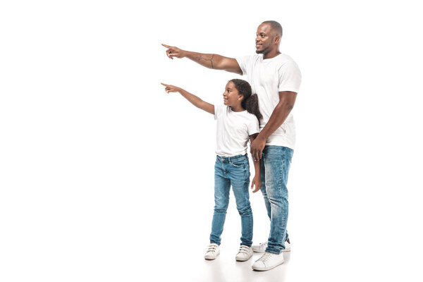 smiling african american father and daughter pointing with fingers and looking away on white background