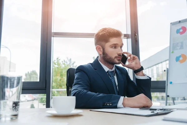 Joven Hombre Negocios Hablando Teléfono Inteligente Mientras Está Sentado Escritorio — Foto de Stock