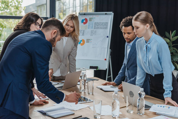мультикультурные предприниматели рассматривают документы на рабочем столе во время деловой встречи
