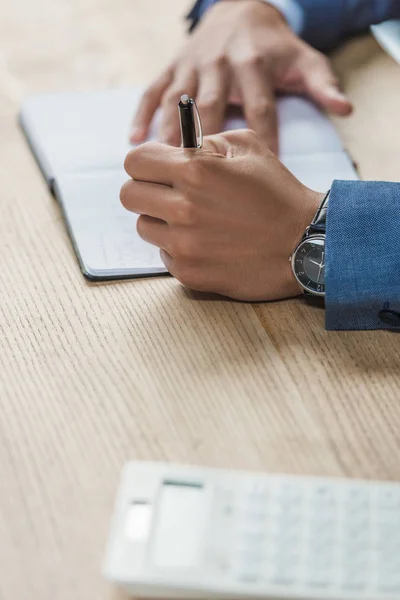 Ausgeschnittene Ansicht Eines Geschäftsmannes Der Notizbuch Auf Holztisch Schreibt — Stockfoto