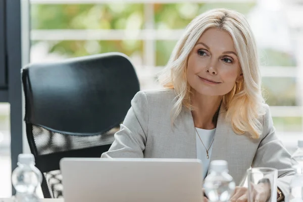 attentive, mature businesswoman smiling in meeting room