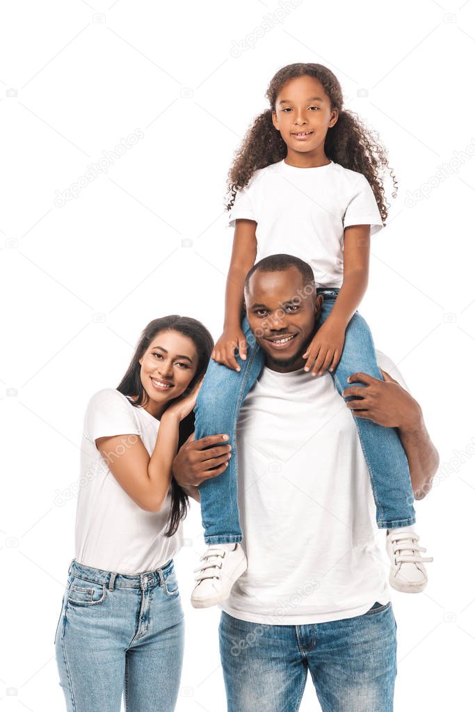 happy african american woman leaning on shoulder of husband piggybacking adorable daughter isolated on white