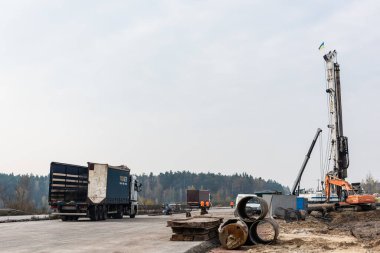 LVIV, UKRAINE - OCTOBER 23, 2019: truck near cars and hoisting crane against sky  clipart