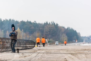 LVIV, UKRAINE - 23 Ekim 2019: koruyucu maskeli ve metal yapının yanında duran gözlüklü kaynakçının seçici odak noktası