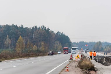 LVIV, UKRAINE - 23 Ekim 2019: Kamyon ve arabaların yanında duran üniformalı işçilerin arka görüntüsü 