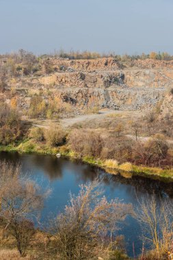 Göl kıyısında mavi suyu olan taşlar ve ağaçlar. 