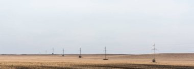 Bulutlu gökyüzüne karşı altın alanın yakınındaki enerji hattı konsepti 