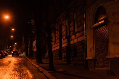 LVIV, UKRAINE - OCTOBER 23, 2019: building near road with car in night clipart