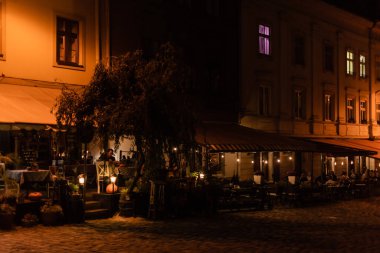 LVIV, UKRAINE - 23 Ekim 2019: insanlar akşamları teraslı kafede oturuyorlar. 
