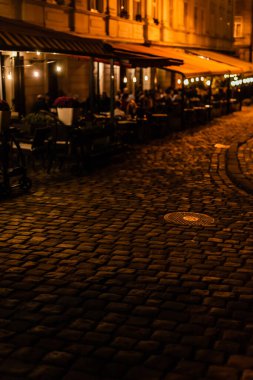 selective focus of paving stones on road near cafe with terrace  clipart