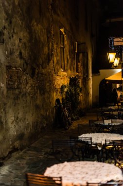 selective focus of bicycle near old wall and tables with chairs on terrace  clipart