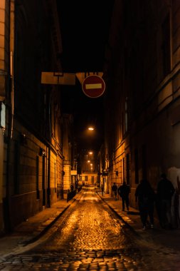 LVIV, UKRAINE - 23 Ekim 2019: lviv 'deki karanlık sokakta yürüyen insanların silueti 